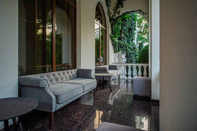Zona lounge MiaDora cu canapele, plante și tavan din lemn, la apus