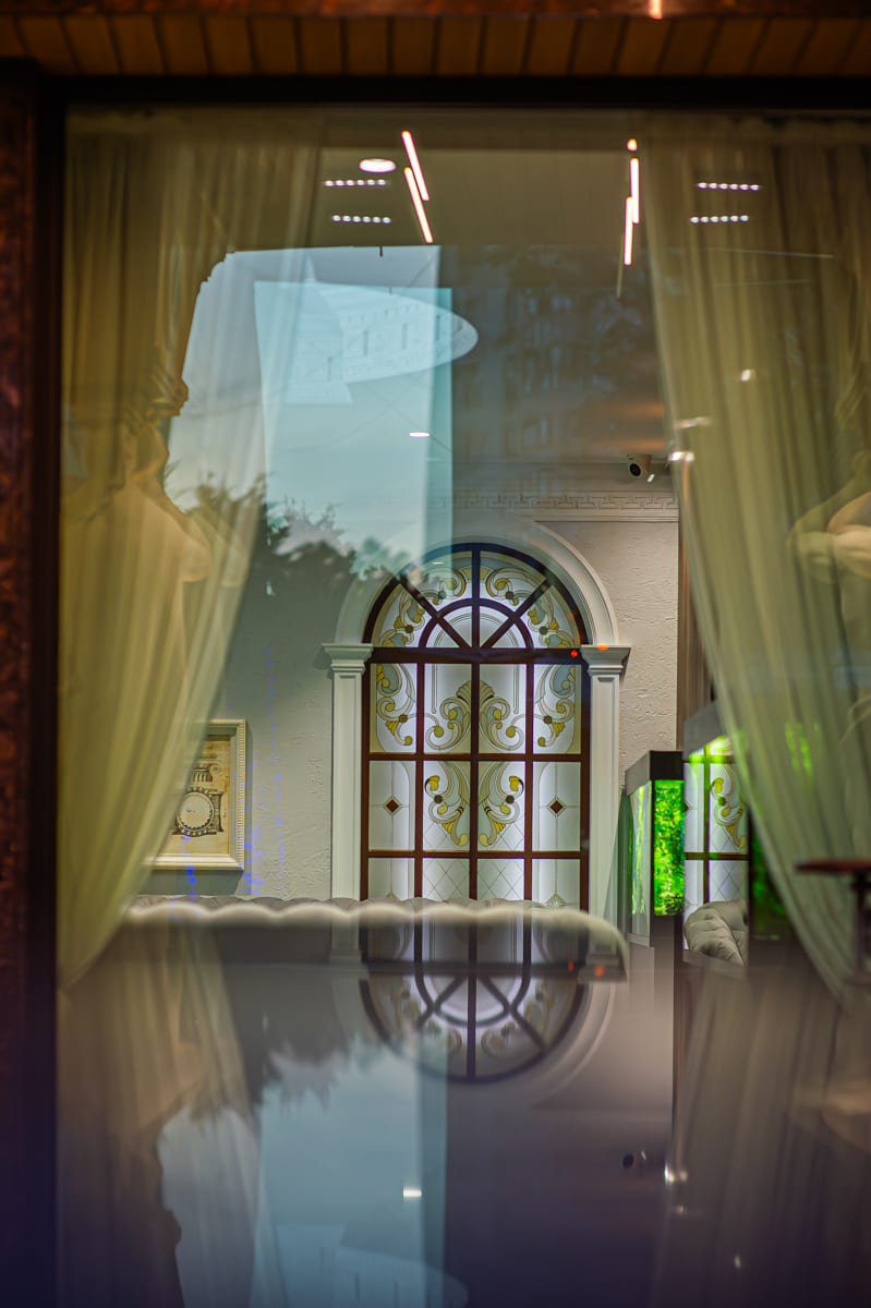 Detaliu arhitectural MiaDora: fereastră arcuită cu draperii, la apus
