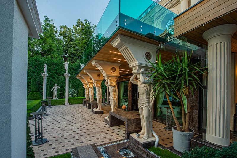 Fațada clasică MiaDora cu cariatide, coloane și balcon de sticlă, la apus