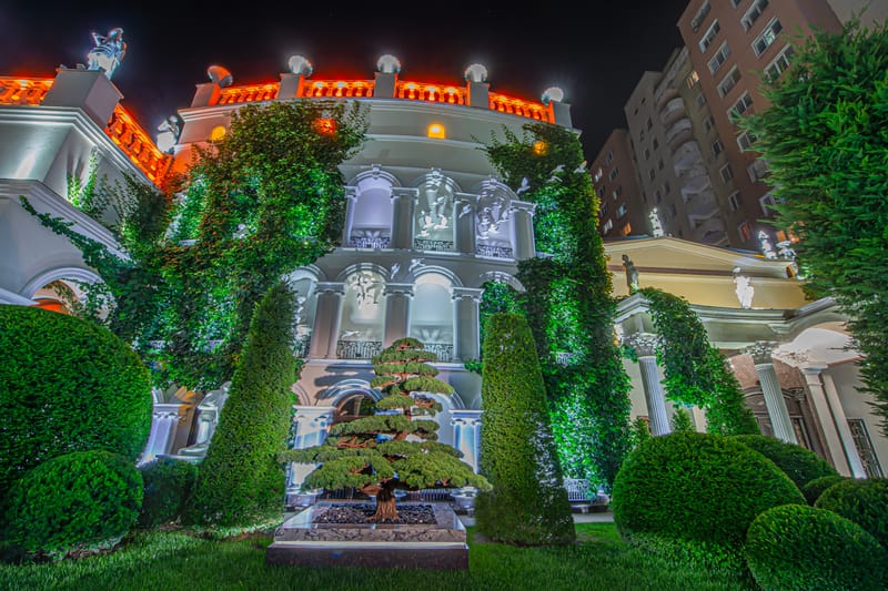 MiaDora iluminată noaptea: grădina, fântâna și fațada clasică