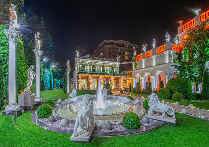 MiaDora iluminată noaptea: grădina, fântâna și fațada clasică