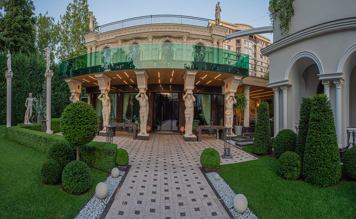 Fațada clasică MiaDora cu cariatide, coloane și balcon de sticlă, în lumina zilei