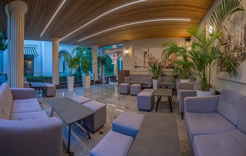 Zona lounge MiaDora cu canapele, plante și tavan din lemn, la apus