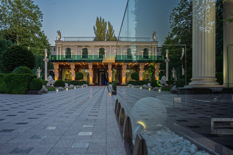 Grădina MiaDora cu alei pavate, statui pe coloane și la apus