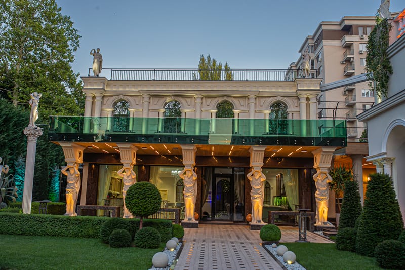 Fațada clasică MiaDora cu cariatide, coloane și balcon de sticlă, la apus